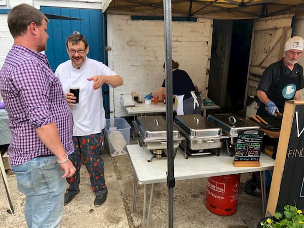 Tony working at the BBQ whilst Ian takes on some sustanance