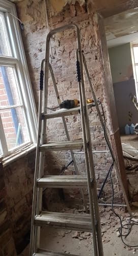 Ladder against a wall to allow removal of plaster on a lintel