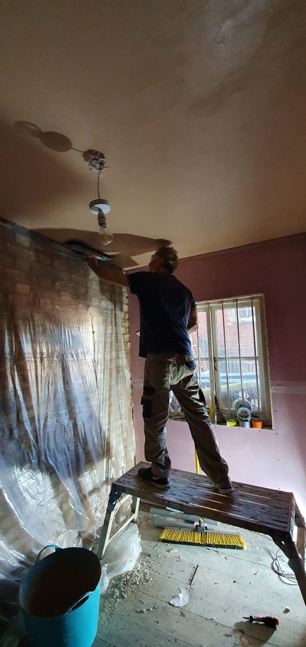 Standing on a platform to give him height required to plaster ceiling