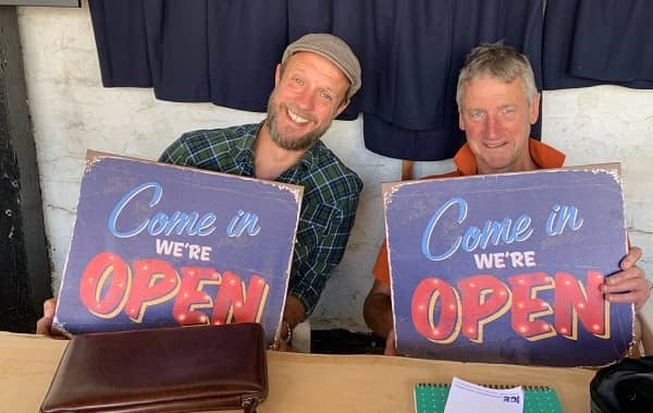 Richard and Will with signs with we are open on them