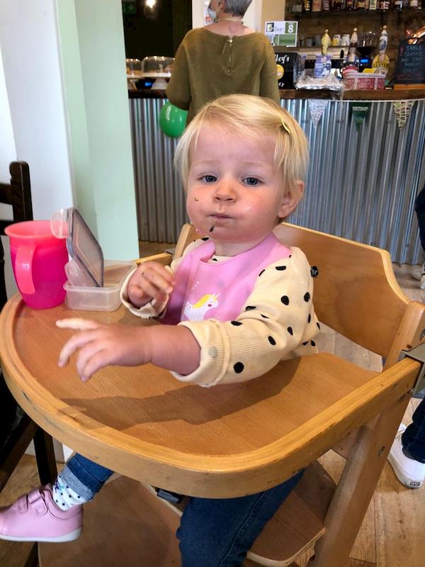 Baby in high stool enjoying a cake