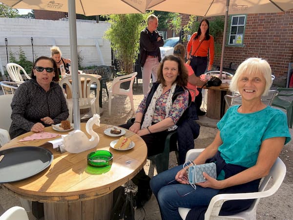 Three ladies enjoying their cake with more waiting behind them