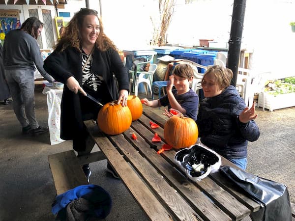 Mum supervising a couple of kids who are enjoying carving pumpkins