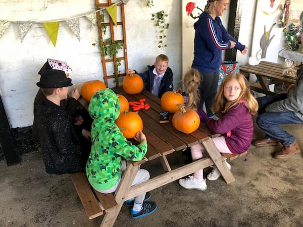 Table of younger customers carving pumpkins