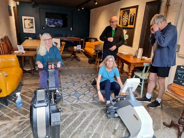 Two ladies rowing being supported by onlookers