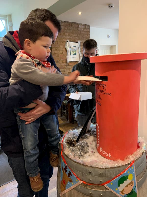 A small boy being lifted up so he can post a letter to Santa