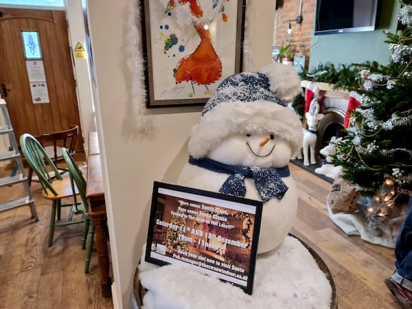 Snowman and snow on top of a barrel inside The Pub
