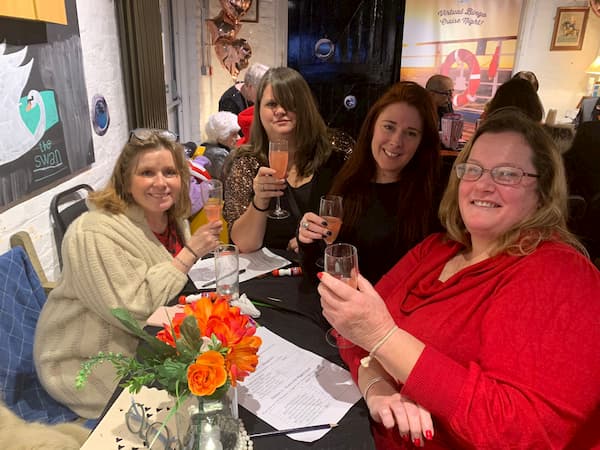 Happy table of ladies raising their glasses - cheers!