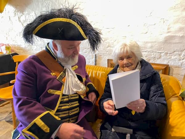 The Town Crier with Rene looking at her card from The Queen