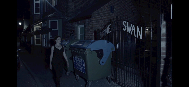 At night, an actress walking past the main gates at The Swan.