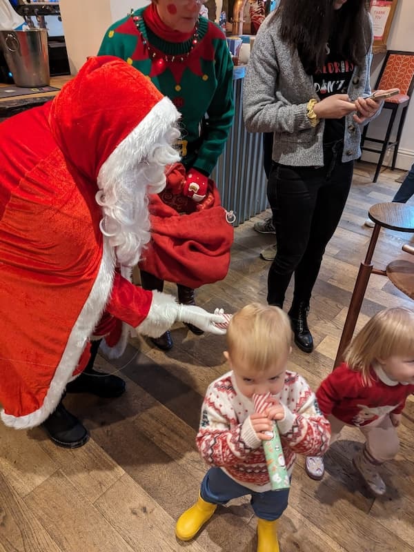 Santa trying to get the attention of two youngsters.
