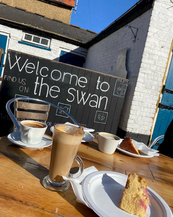Welcome to The Swan sign in background, coffee and cake in the foreground