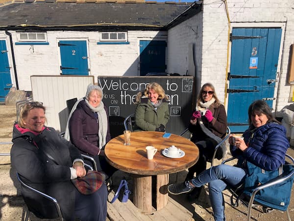 Table of ladies outside enjoying the sun, cake and coffee