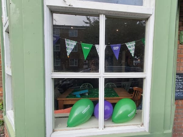 Macmillan balloons and bunting in the front window of the bar