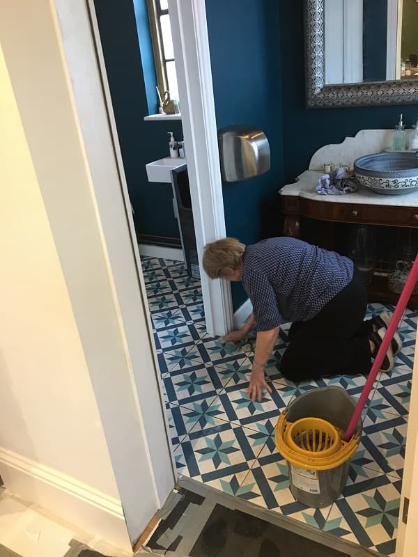 Down on hands and knees cleaning the floor tiles