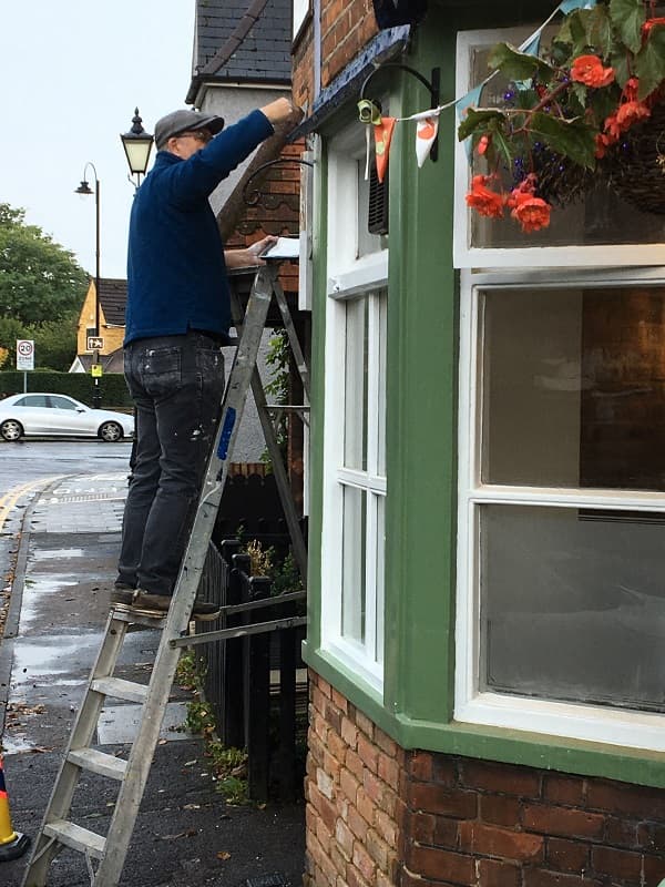 Outside the pub in the street up a ladder