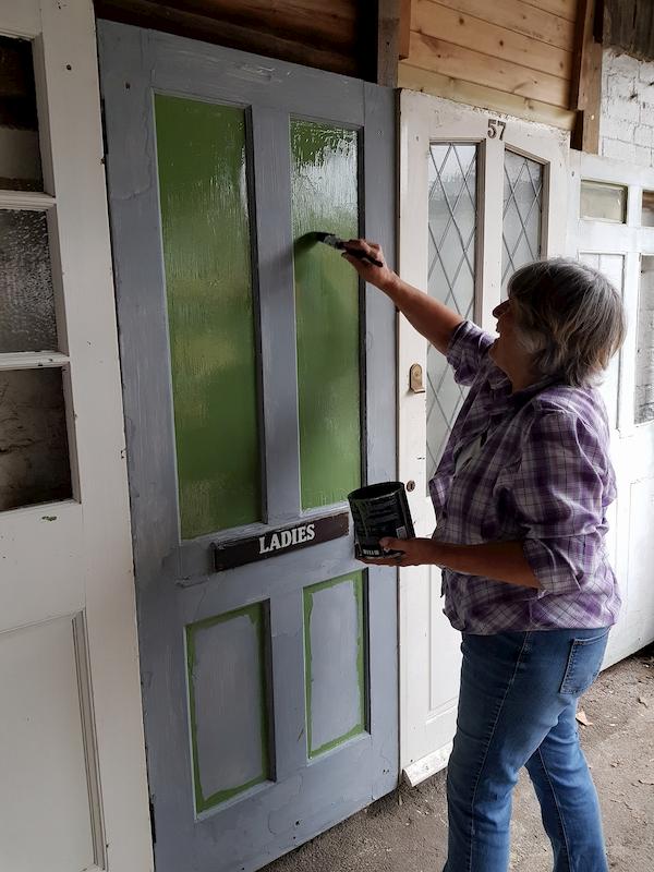 Carole painting the doors underneath the awning