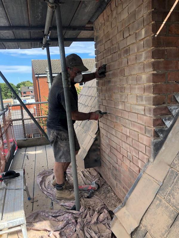 John chiseling out the old mortar on one of the chimneys