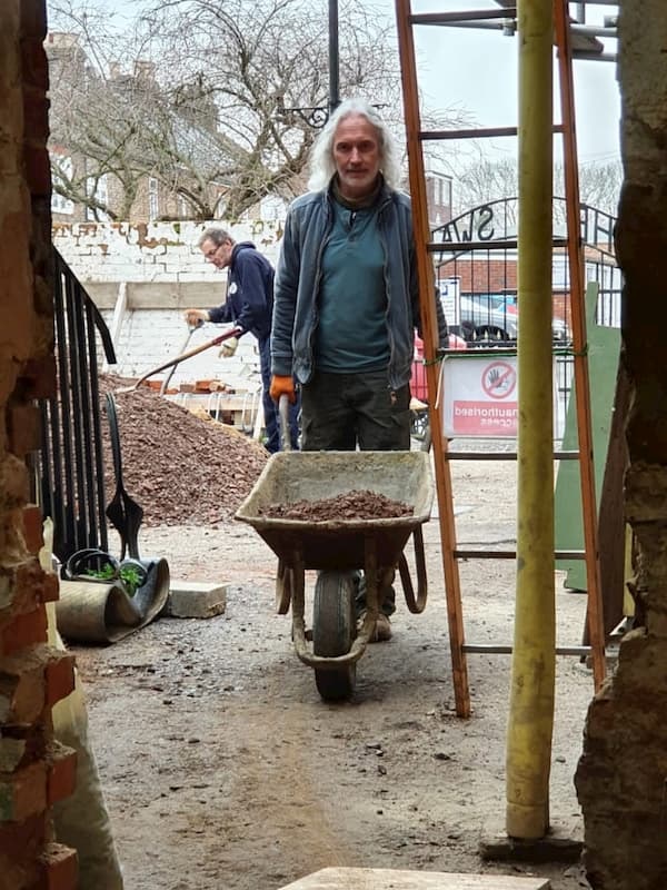 Tony barrowing screed into the building