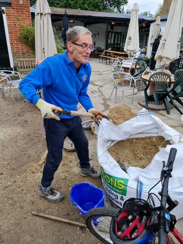 Trevor filling the wheel barrow with sand