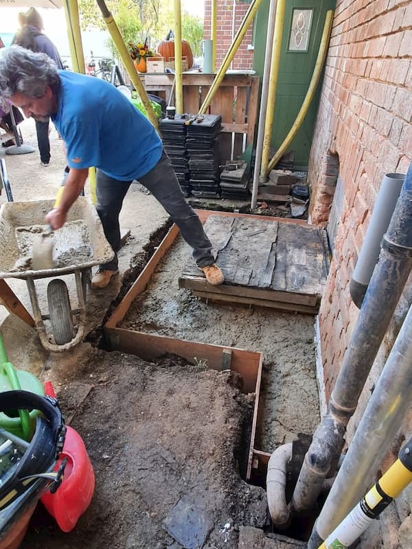 Thomas shovelling cement into the hole