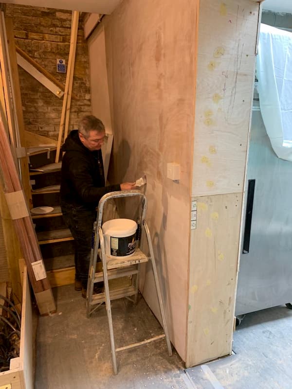 Painting the fresh plaster that is by the stairs to The School House