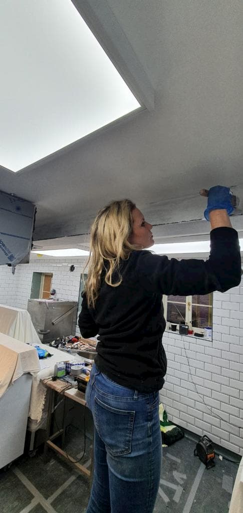 Lexie painting the main steel girder in The Kitchn