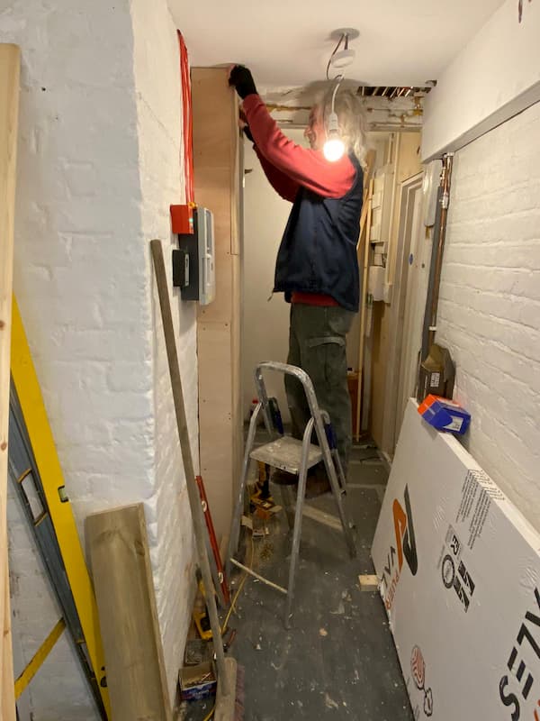 Tony working to box in the electrical panels in the hallway