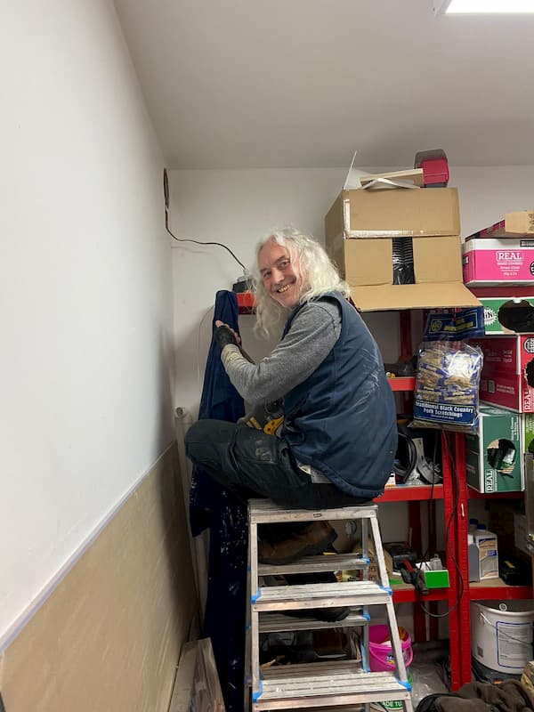 A happy Tony atop a ladder fitting an extractor fan