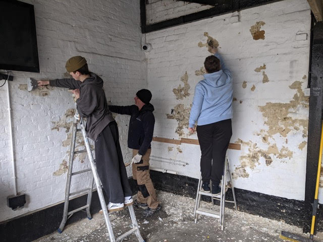 Students stripping the walls underneath the covered are in The Courtyard.