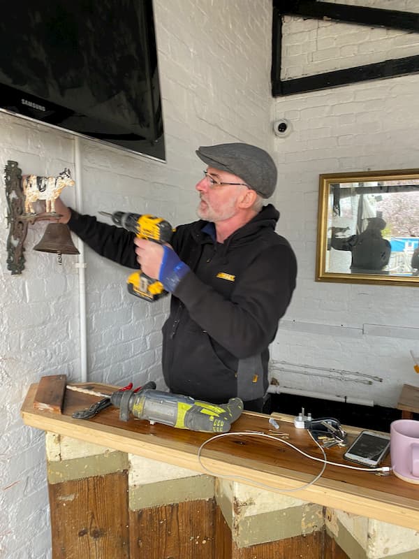 Volunteer attaching a bell just above the bar.