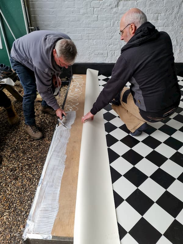 Two men working on laying the laminate floor in the covered area.