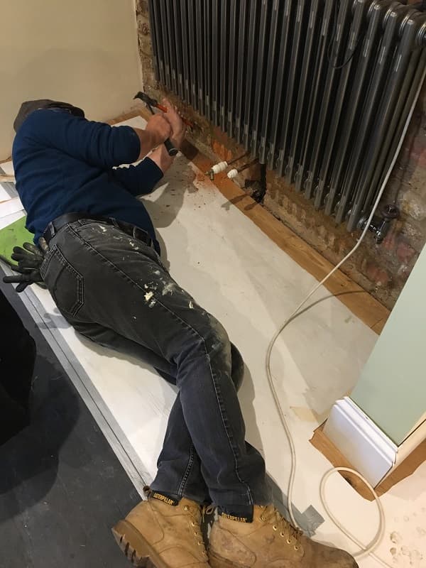 Adrian lying on floor fixing the skirting to the wall