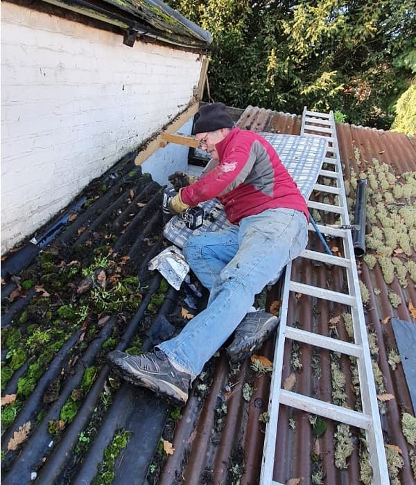 Lying on ladder removing old aluminium roof