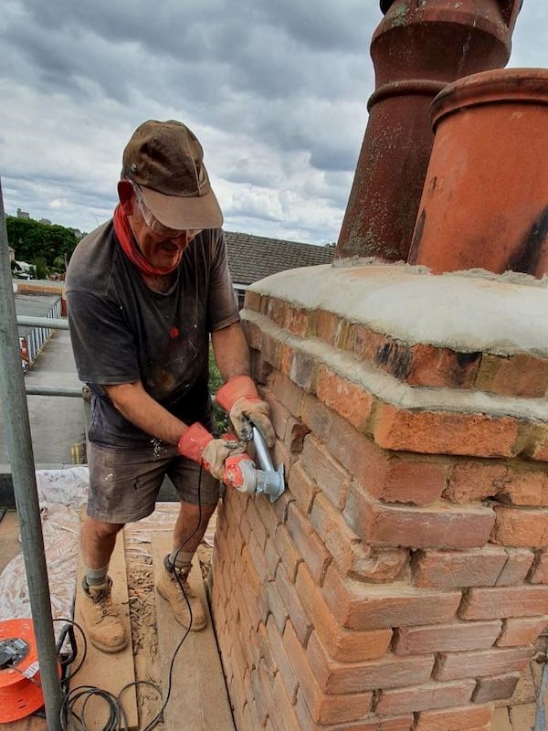 John chiseling out the old mortar on one of the chimneys