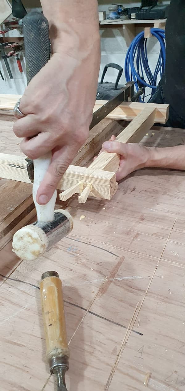 Tapping in small wooden posts into the frame to finish it off 